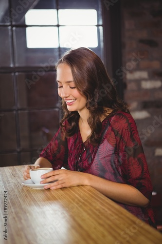 Smiling brunette enjoying cup of coffee