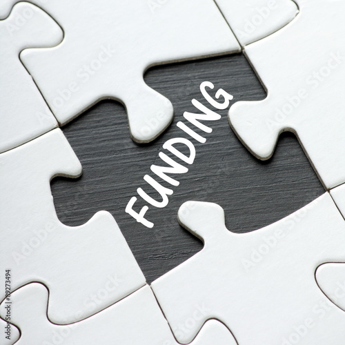 The word Funding in white text on a blackboard as revealed by a missing jigsaw puzzle piece