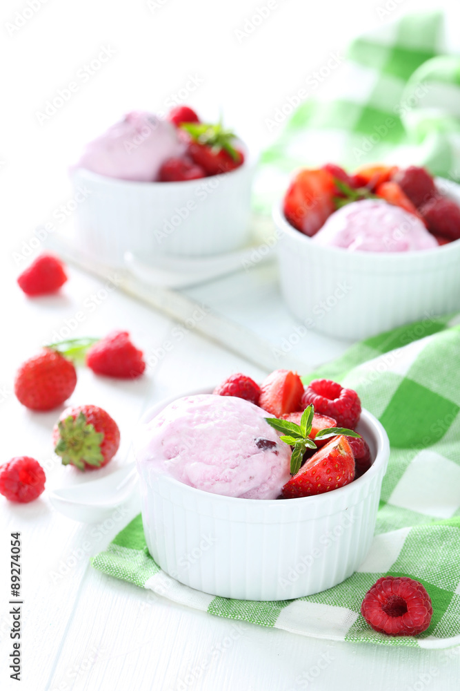 Ice cream in bowl with strawberries and raspberries on white woo Ice cream in bowl with strawberries and raspberries on white woo