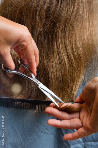 hands of hairdresser trimming hair with scissors and comb