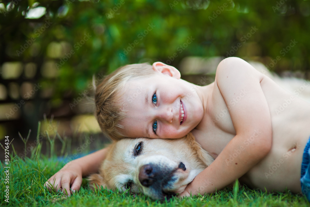 Smiling happy boy and his golden retriever in the grass Smiling happy boy and his golden retriever in the grass
