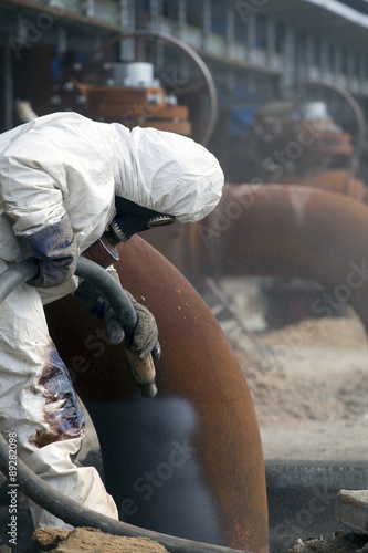 Canvas-taulu Worker in protective equipment cleans the metal construction before painting the