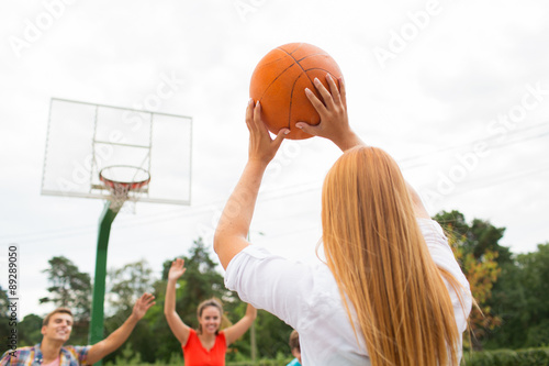 group of happy teenagers playing basketball