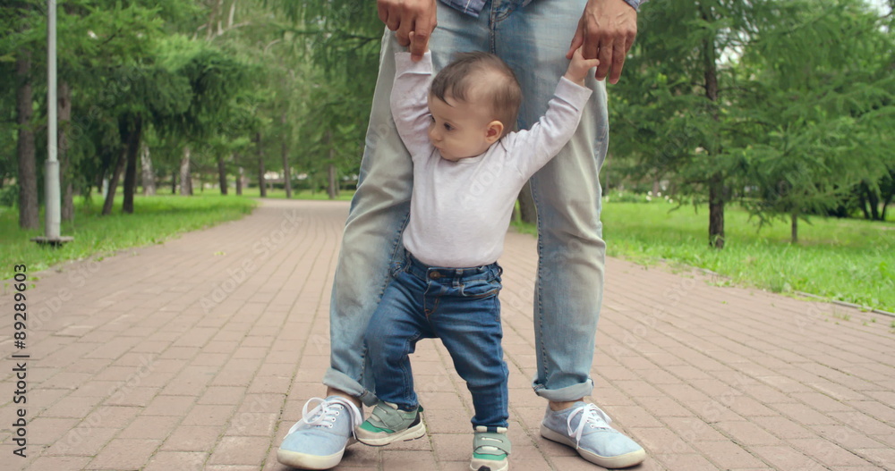 Lovely baby boy making tottering steps with help of his father Lovely baby boy making tottering steps with help of his father