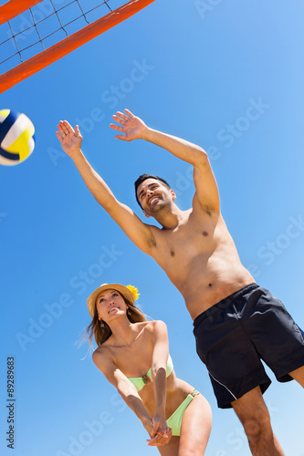  Young smiling couple playing volleyball