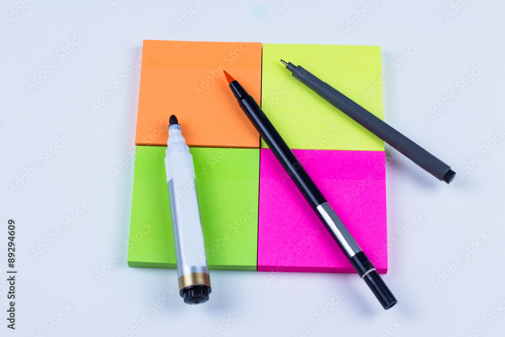 Square of colored sticky note with pens and markers Square of colored sticky note with pens and markers