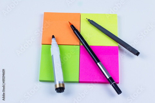 Square of colored sticky note with pens and markers