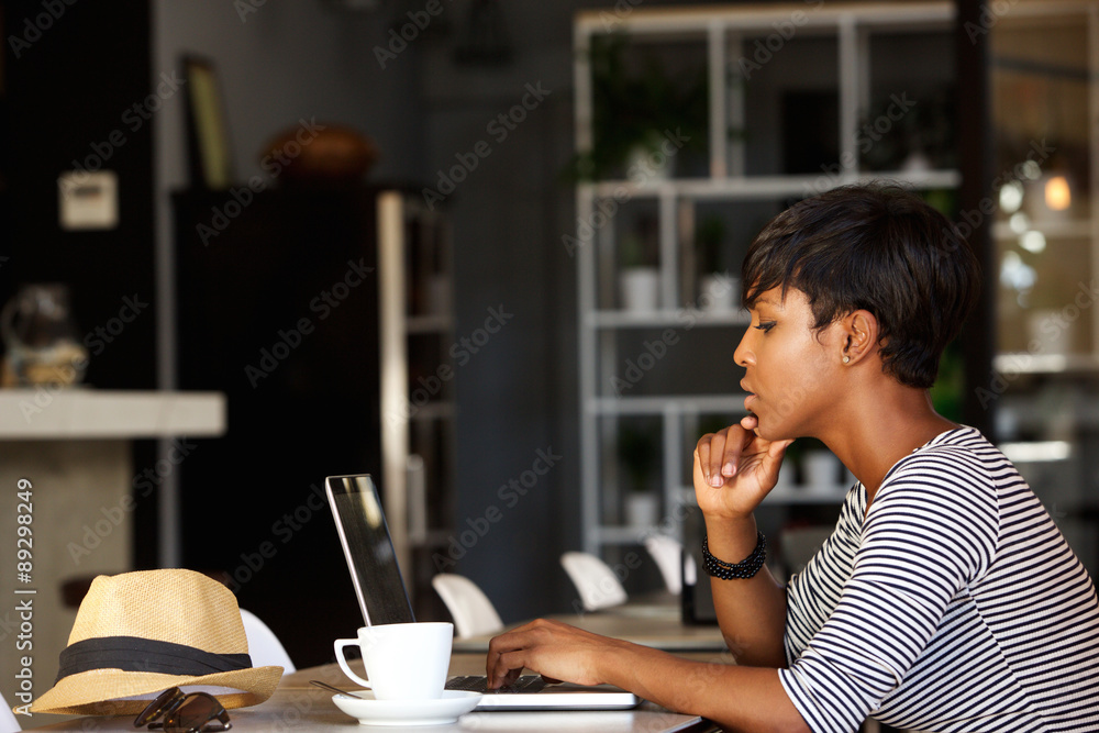 African american woman using laptop at cafe