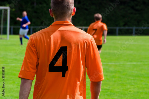 Fußballspieler im orangen Trikot von hinten 