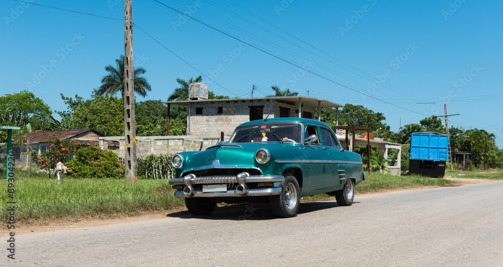 Kuba auf der Strasse fahrender grün blauer amerikanischer Oldtimer im Landesinneren.