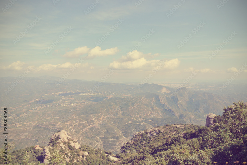 Panoramic view from the top of Montserrat mountain, located close to Barcelona in Catalonia, Spain. Image filtered in faded, washed out, retro style with soft focus; nostalgic vintage travel concept.