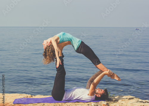 Couple are practicing acroyoga on the sea coast 