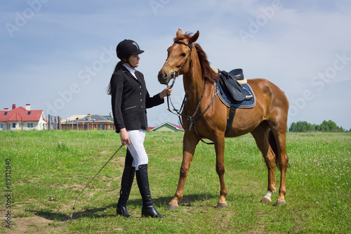 Beautiful young girl jockey talks with her horse