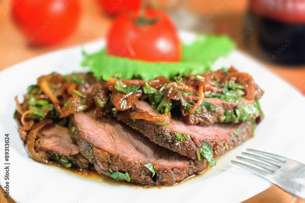 Beef sliced with a sauce of grilled onions and parsley on a white plate