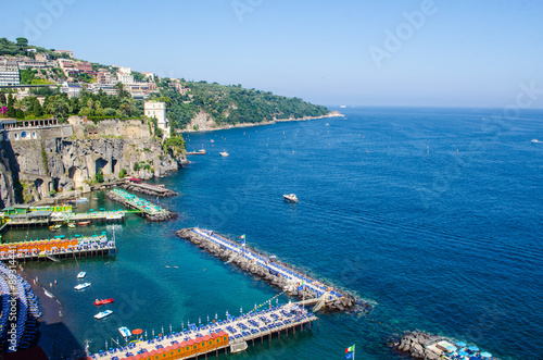 view of coast of italian city sorrento where people may relay on a wooden quay offseting sandy beach. photo