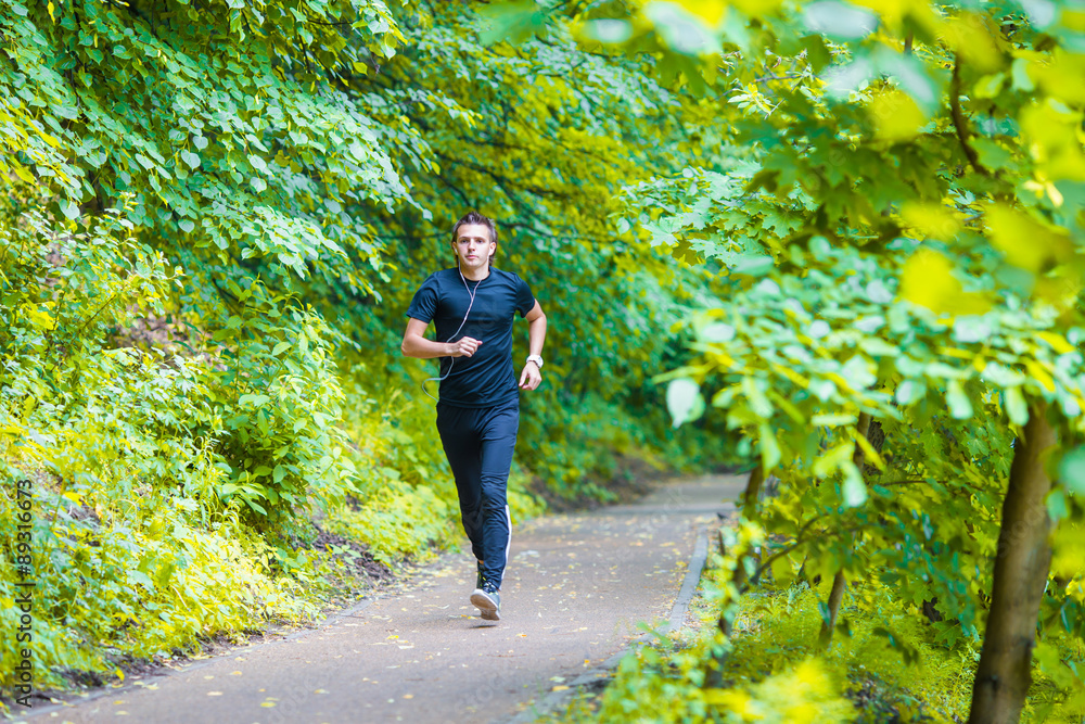 Sporty fit young man jogging while listening music on
