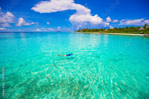 Young man snorkeling in clear tropical turquoise waters