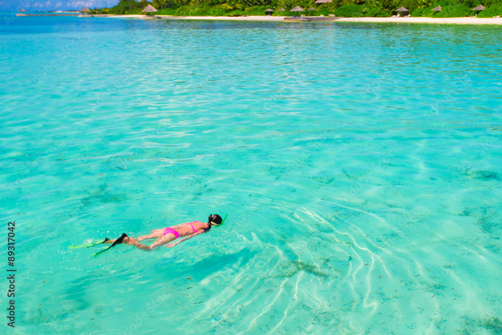 Young girl snorkeling in tropical water on vacation