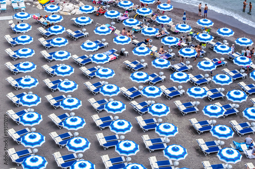 aerial view of blue and white parasols situated on a beach in italy.