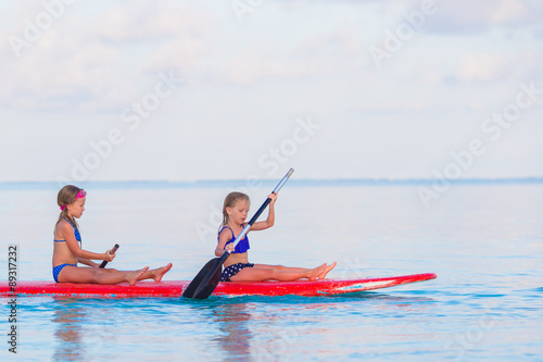 Little cute girls swimming on surfboard during summer vacation © travnikovstudio