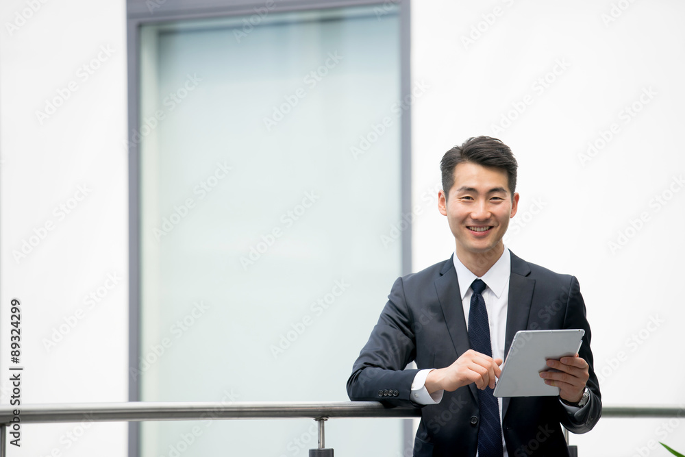 Young asian businessman using tablet, mobile phone in the office Young asian businessman using tablet, mobile phone in the office