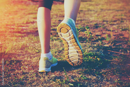 Girl jogging outside. Feet running on grass