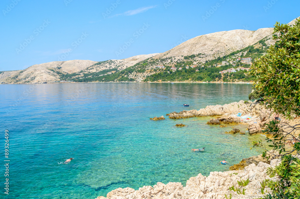 Beautiful rocky beach with crystal clear sea and people snorkeling Beautiful rocky beach with crystal clear sea and people snorkeling