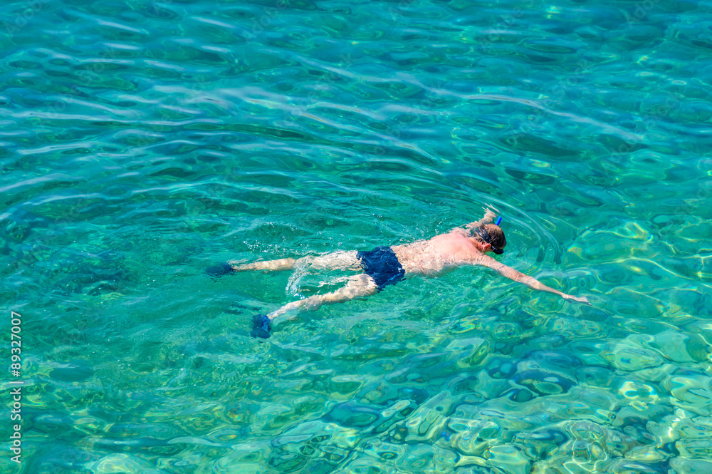 A man snorkeling in the crystal clear sea or ocean