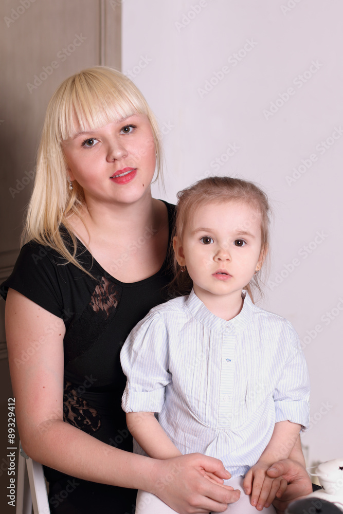Cute little blond girl in striped shirt sitting on lap of mother Cute little blond girl in striped shirt sitting on lap of mother