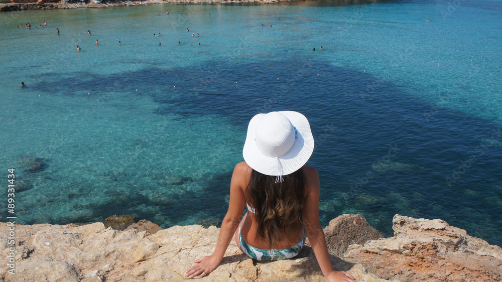 Woman with a pamela hat sitting over a cliff Woman with a pamela hat sitting over a cliff