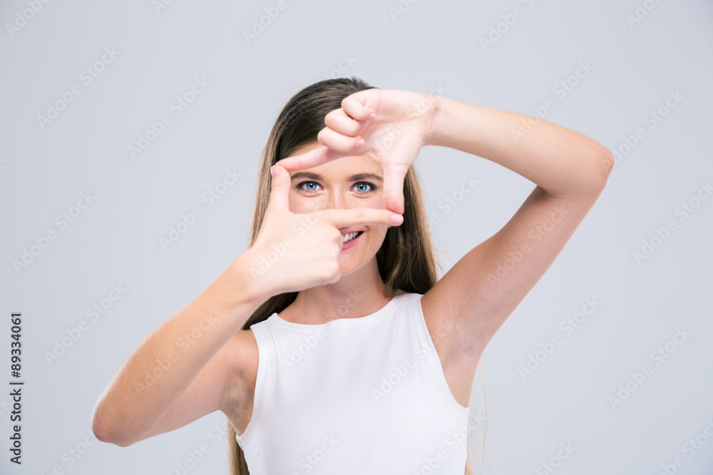 Happy female teenager looking at camera through frame gesture Happy female teenager looking at camera through frame gesture