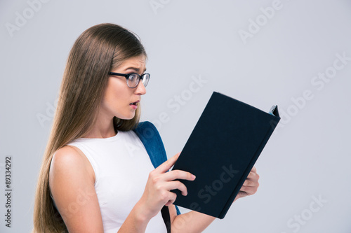 Amazed female teenager reading book