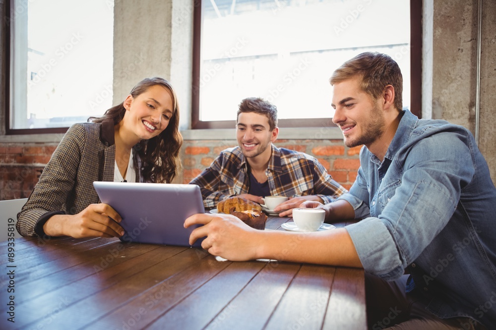 Smiling friends holding tablet and looking at it Smiling friends holding tablet and looking at it