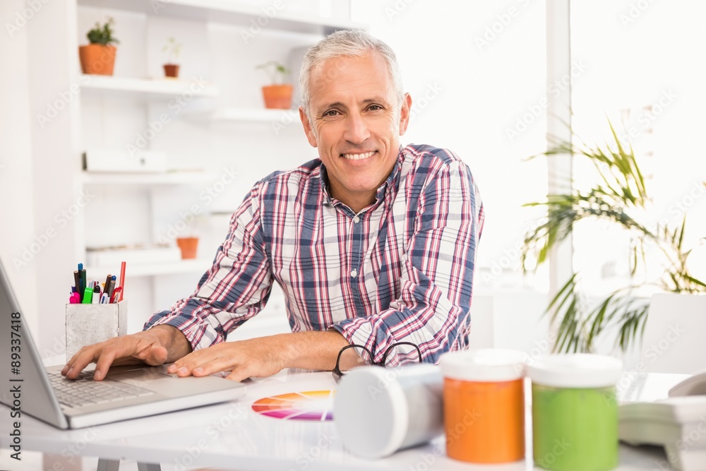 Smiling casual designer working with laptop