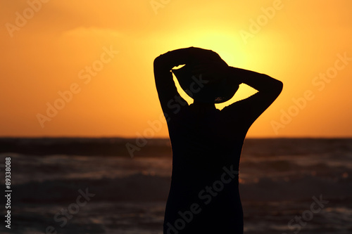  female form with the hat against the sea at sunset