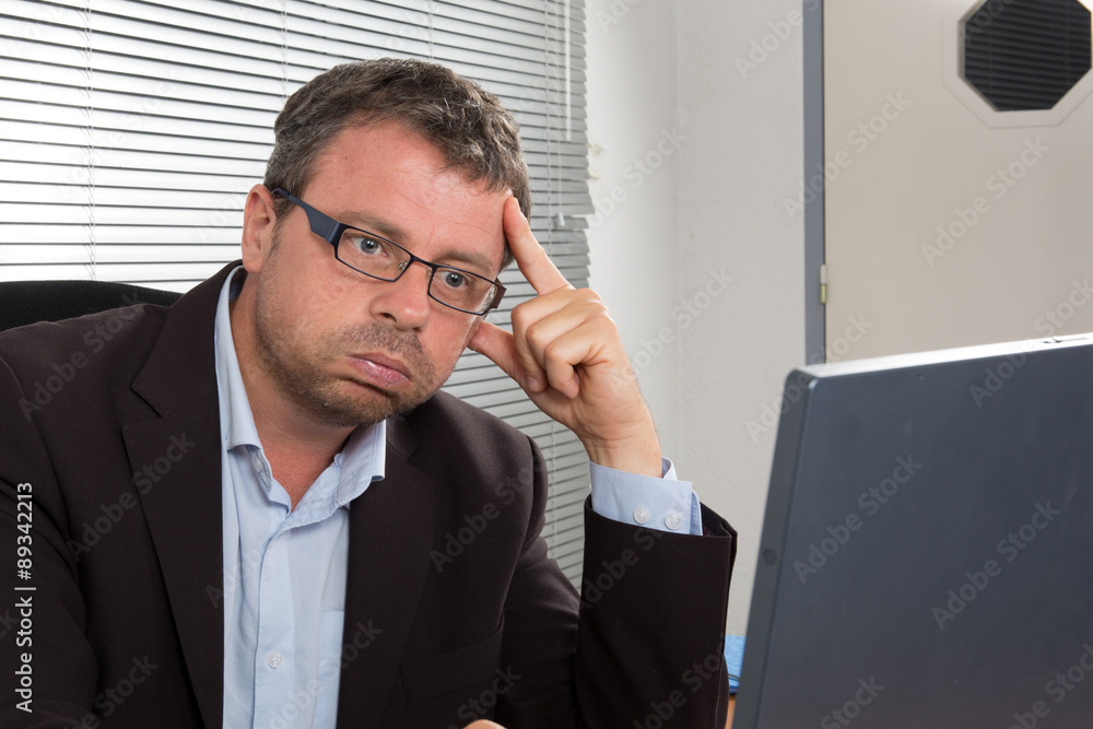 Pensive mature businessman looking at laptop with concentration Pensive mature businessman looking at laptop with concentration