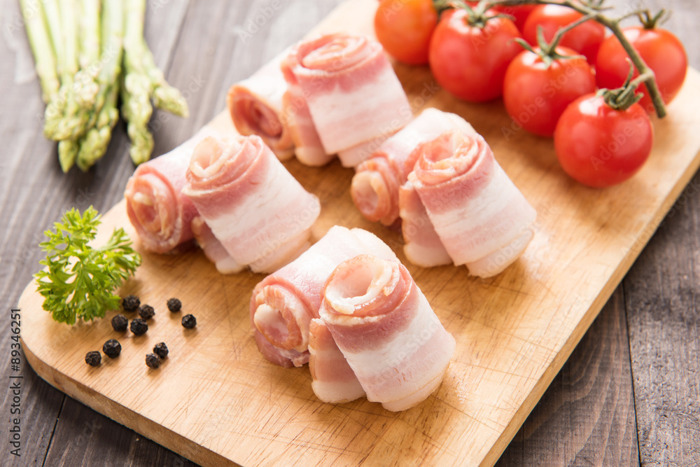 Bacon rolls with tomato, asparagus on wooden background Bacon rolls with tomato, asparagus on wooden background