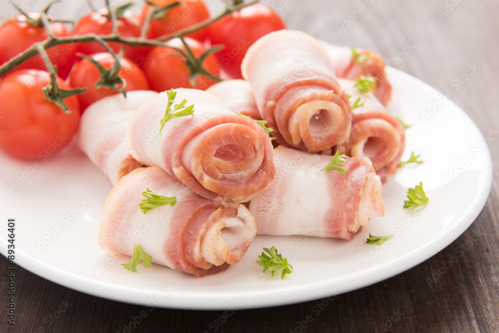 Bacon rolls with tomato on wooden background
