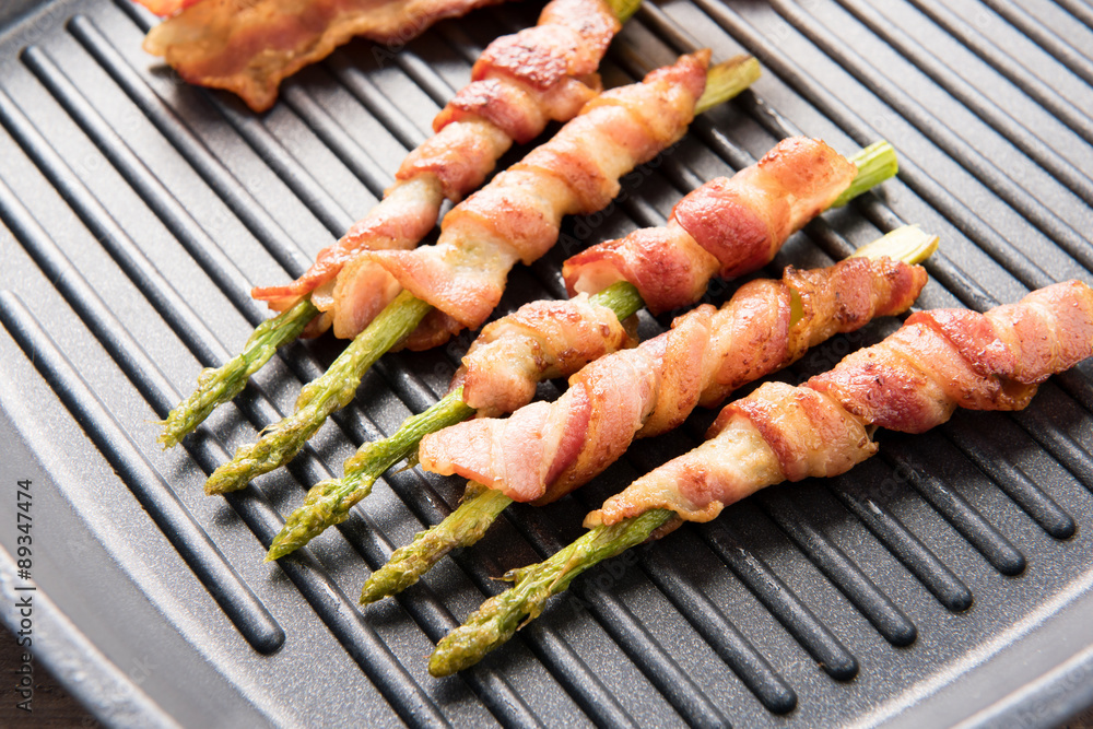 Bacon slice and asparagus wrapped in bacon being cooked in fryin