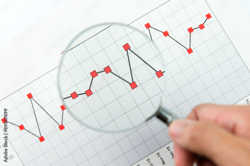 Magnifying glass over financial graph Magnifying glass over financial graph