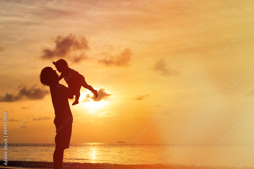Fototapeta premium Father and daughter silhouettes on beach at sunset