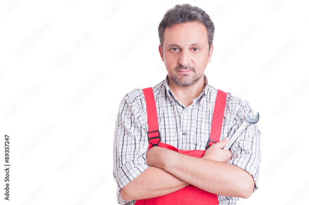 Serious and trustworthy mechanic holding wrench with arms crosse Serious and trustworthy mechanic holding wrench with arms crosse