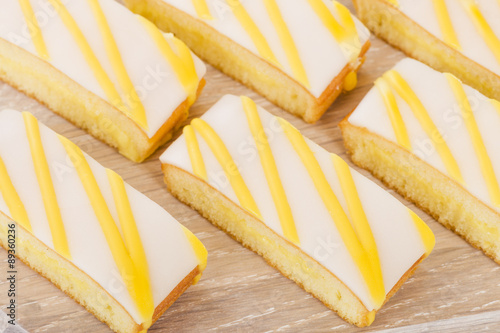 Foto Lemon Drizzle Cake - Slices of lemon cake topped with icing.