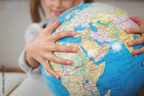 Pupil holding globe in a classroom