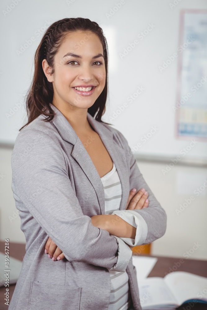Pretty teacher with arms crossed in a classroom