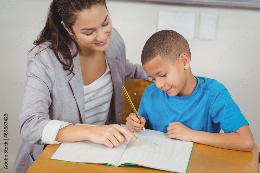Pretty teacher helping pupil at his desk Pretty teacher helping pupil at his desk