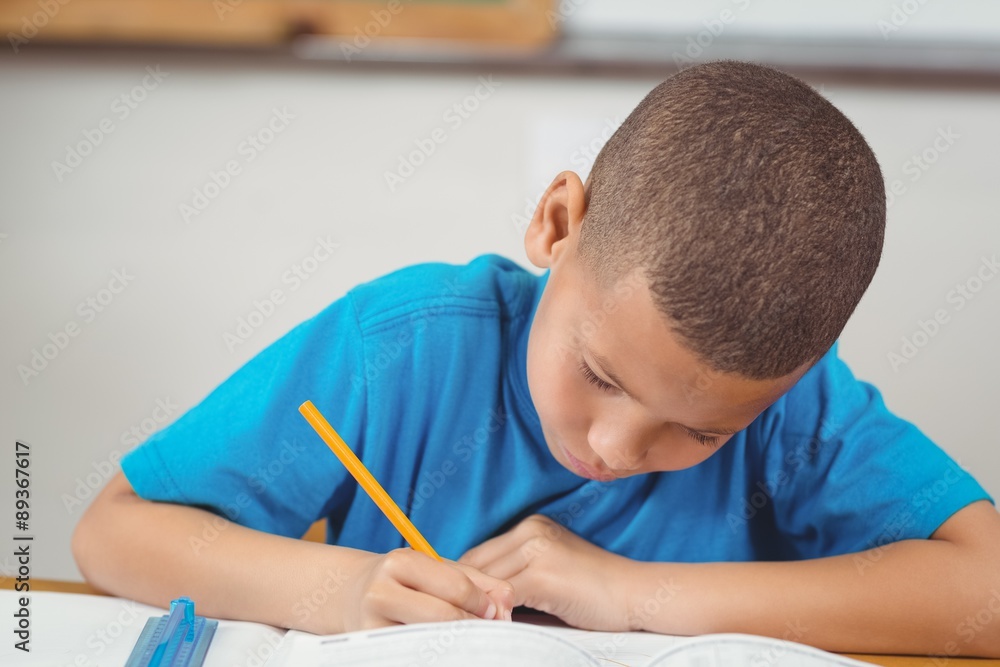 Concentrated pupil working at his desk in a classroom Concentrated pupil working at his desk in a classroom