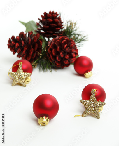 Christmas Balls with gold stars and red pine cones in the background. Focus is on closest star.