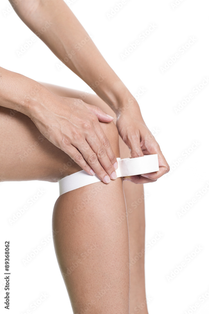 Woman wearing sport tape, knee injured Woman wearing sport tape, knee injured