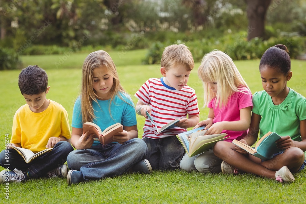 Classmates sitting in grass and reading books Classmates sitting in grass and reading books